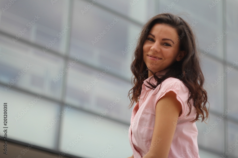 smiling young brunette in front of the business center smiling young brunette in front of the business center