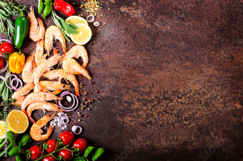 Fresh fish, shrimps with herbs, spices and vegetables on dark vintage background. Healthy food, diet or cooking concept.