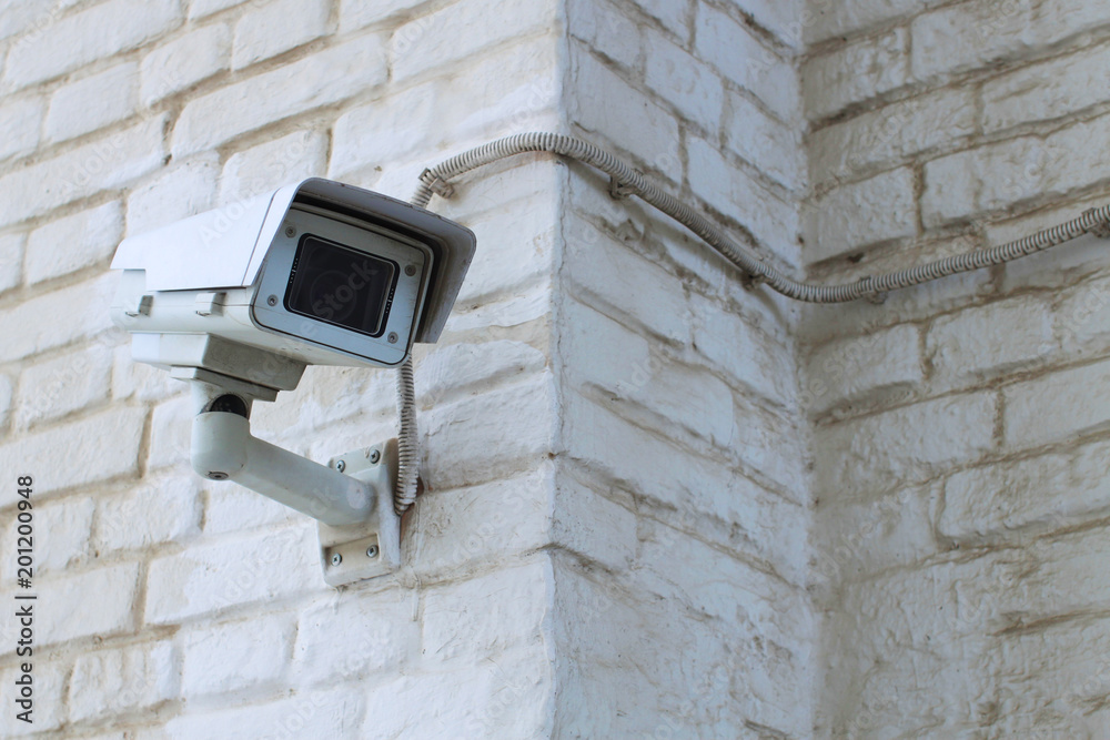 White video surveillance camera on the white wall White video surveillance camera on the white wall
