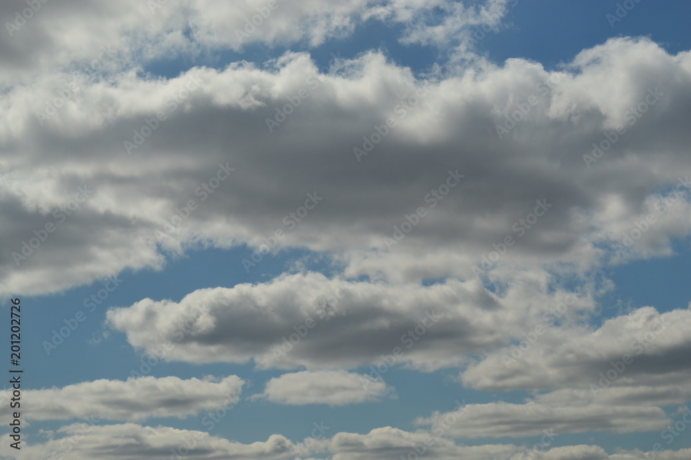 Small cumulus clouds are lit by the sun. The sun is not visible. Small cumulus clouds are lit by the sun. The sun is not visible.