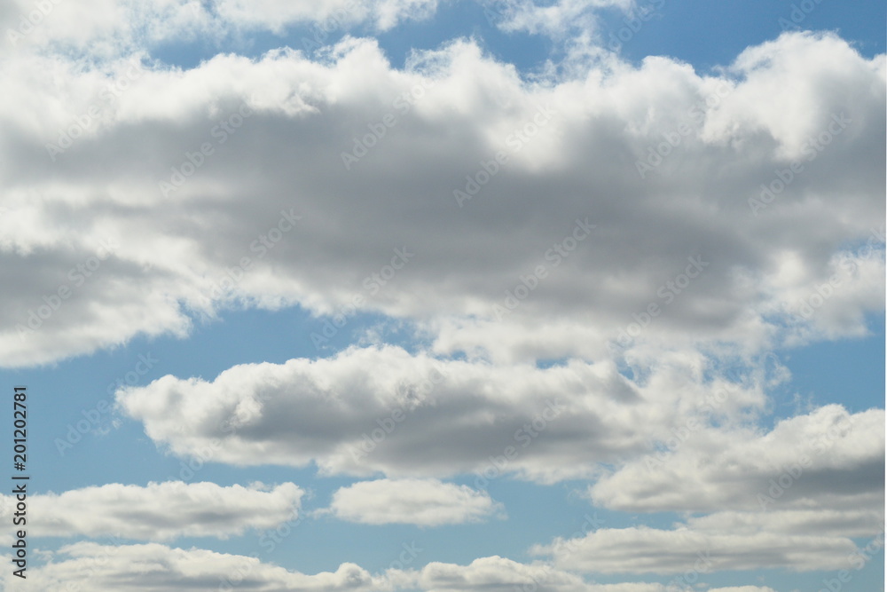 Small cumulus clouds are lit by the sun. The sun is not visible. Small cumulus clouds are lit by the sun. The sun is not visible.