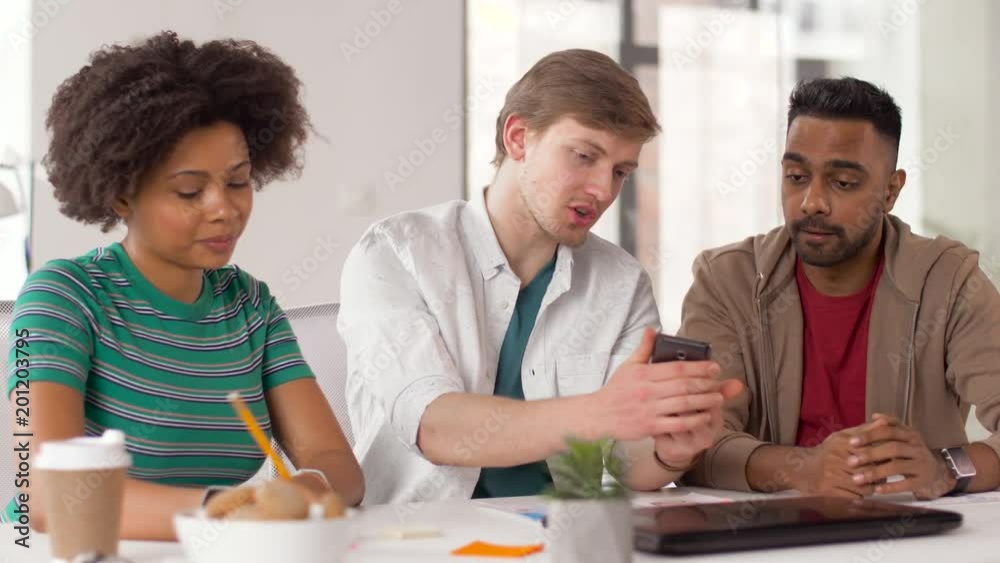 business, technology and creative people concept - man showing smartphone to coworkers at office business, technology and creative people concept - man showing smartphone to coworkers at office