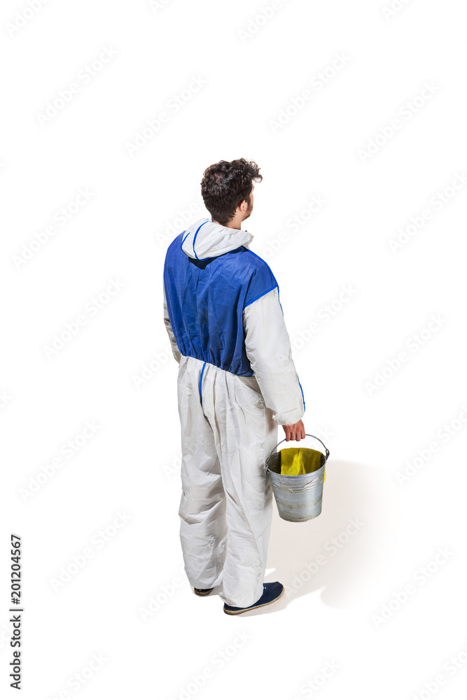 Young male decorator painting with a paint roller climbed a ladder isolated on white background. Young male decorator painting with a paint roller climbed a ladder isolated on white background.