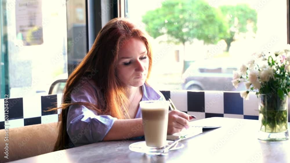 Pretty woman doing notes and drinking coffee in cafe
Pretty woman doing notes and drinking coffee in cafe