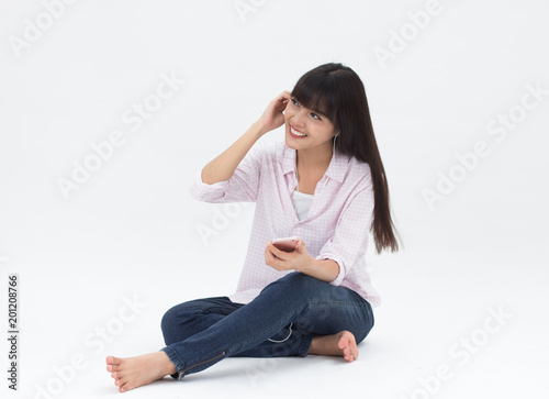 Beautiful Thai girl listen to the music online sitting on white background