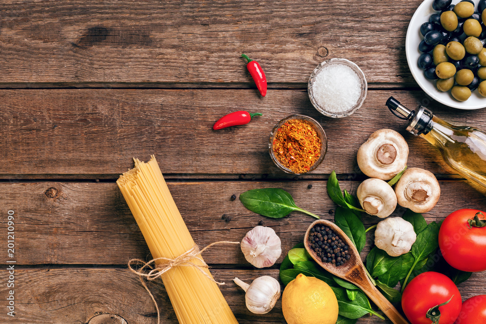 Pasta ingredients - tomatoes, olive oil, garlic, italian herbs, fresh basil, salt and spaghetti on a wooden background with copy space, horizontal, top view Pasta ingredients - tomatoes, olive oil, garlic, italian herbs, fresh basil, salt and spaghetti on a wooden background with copy space, horizontal, top view