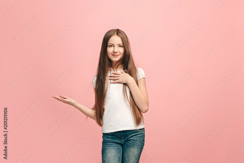 The happy teen girl standing and smiling against pink background.