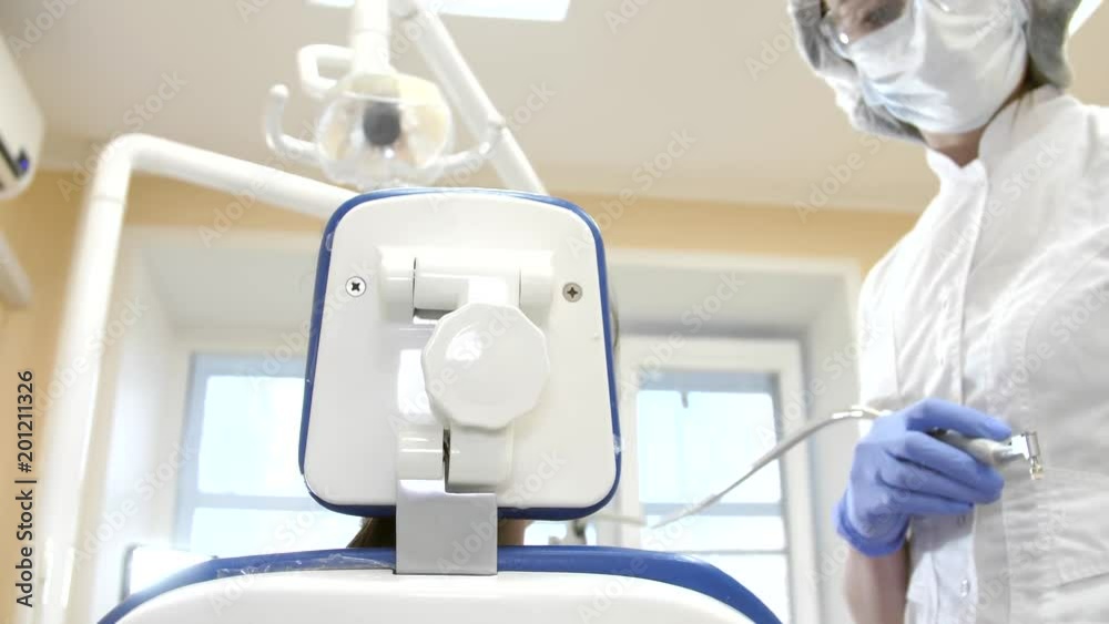 Dentist at work in dental unit with a girl lying client. Patient point of view