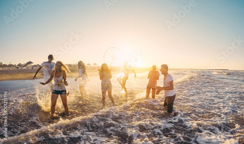 Happy friends having fun on the beach at sunset