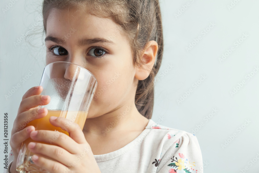 Little cute dark-haired girl drinks a glass of fresh fruit juice Little cute dark-haired girl drinks a glass of fresh fruit juice
