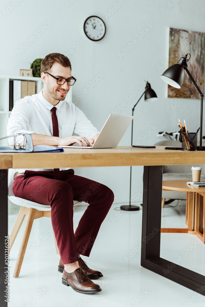 handsome businessman working with laptop in modern office with documents handsome businessman working with laptop in modern office with documents