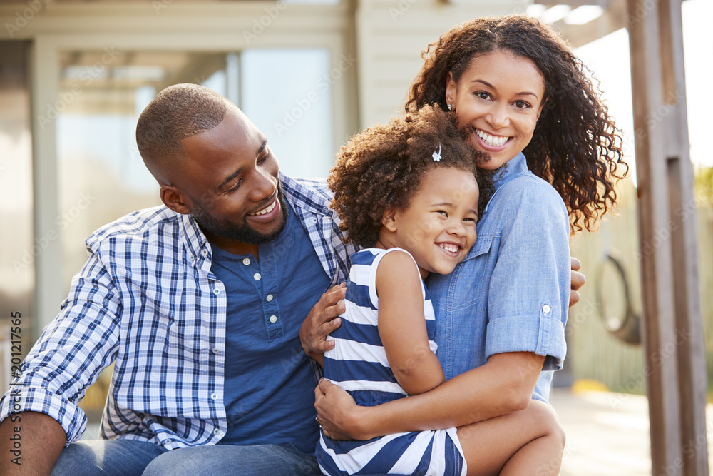 Black family embracing outdoors smiling to camera outside Black family embracing outdoors smiling to camera outside