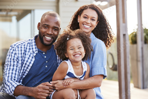 Young black family embracing outdoors and smiling at camera photo