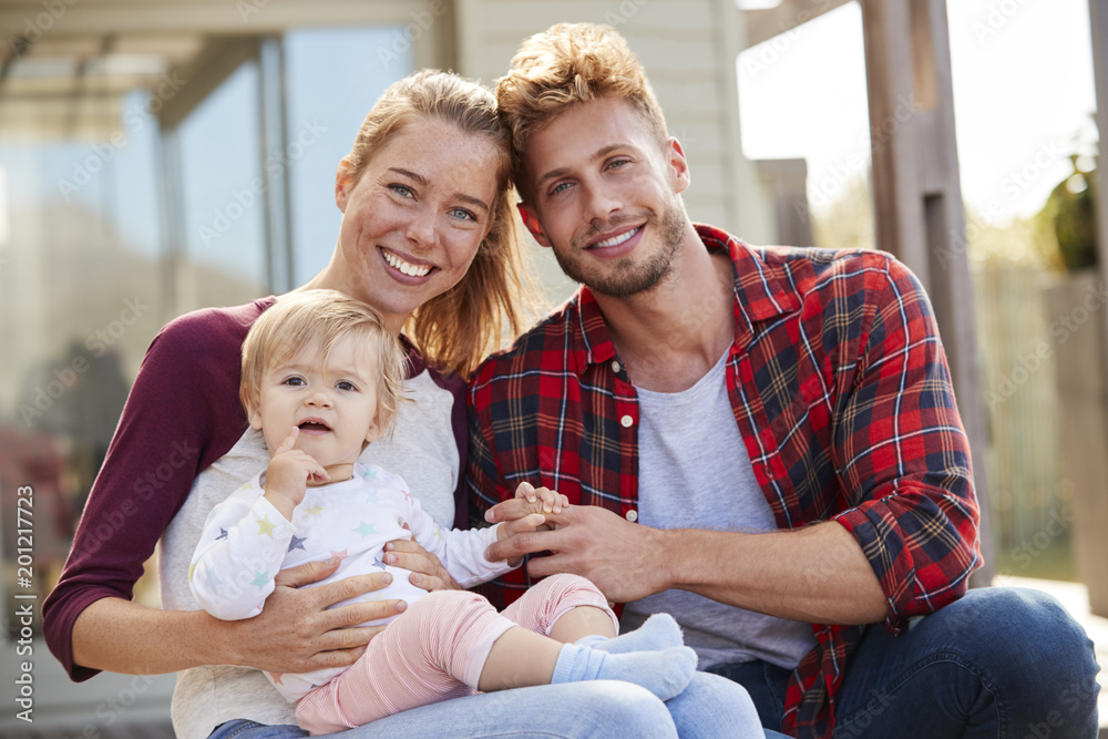 Young white family sitting and smiling at camera outside Young white family sitting and smiling at camera outside