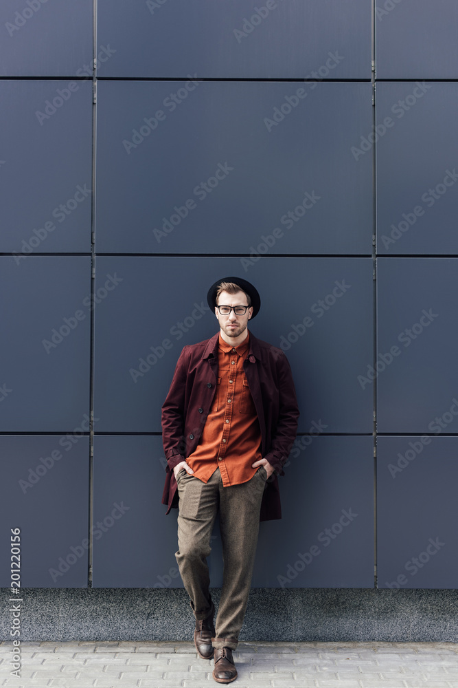 handsome stylish man in hat standing at black wall handsome stylish man in hat standing at black wall
