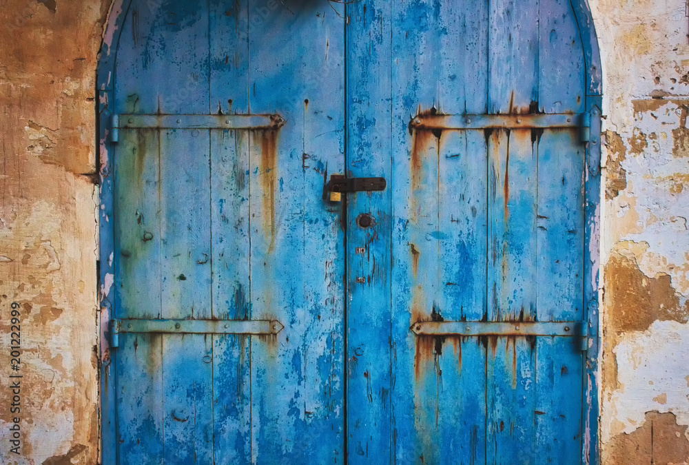 Old blue wooden rustic painted door in the countryside with metal hinges with rust Old blue wooden rustic painted door in the countryside with metal hinges with rust