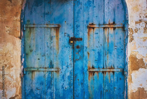 Old blue wooden rustic painted door in the countryside with metal hinges with rust © TenWit