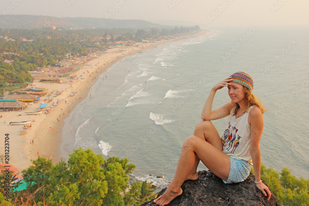Young and beautiful girl wearing a hippie cap sits on top of a mountain and smiling, on a background of Goa beach, Arambol, India. Beach village Arambol Stock Photo | Adobe Stock Young and beautiful girl wearing a hippie cap sits on top of a mountain and smiling, on a background of Goa beach, Arambol, India. Beach village Arambol Stock Photo | Adobe Stock