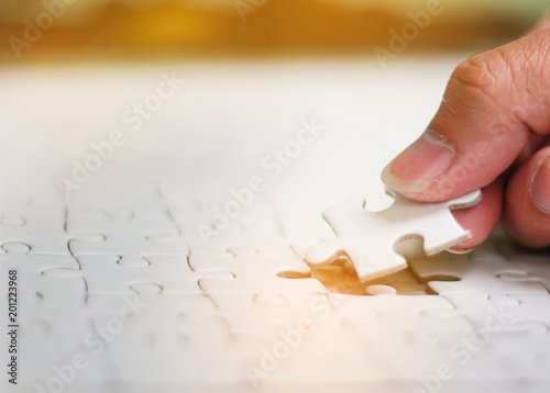 jigsaw puzzle,Pieces of jigsaw on hand with light glow, Woman is trying to connect puzzle piece,Soft focus