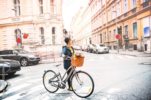Young woman with bicycle in sunny spring town.