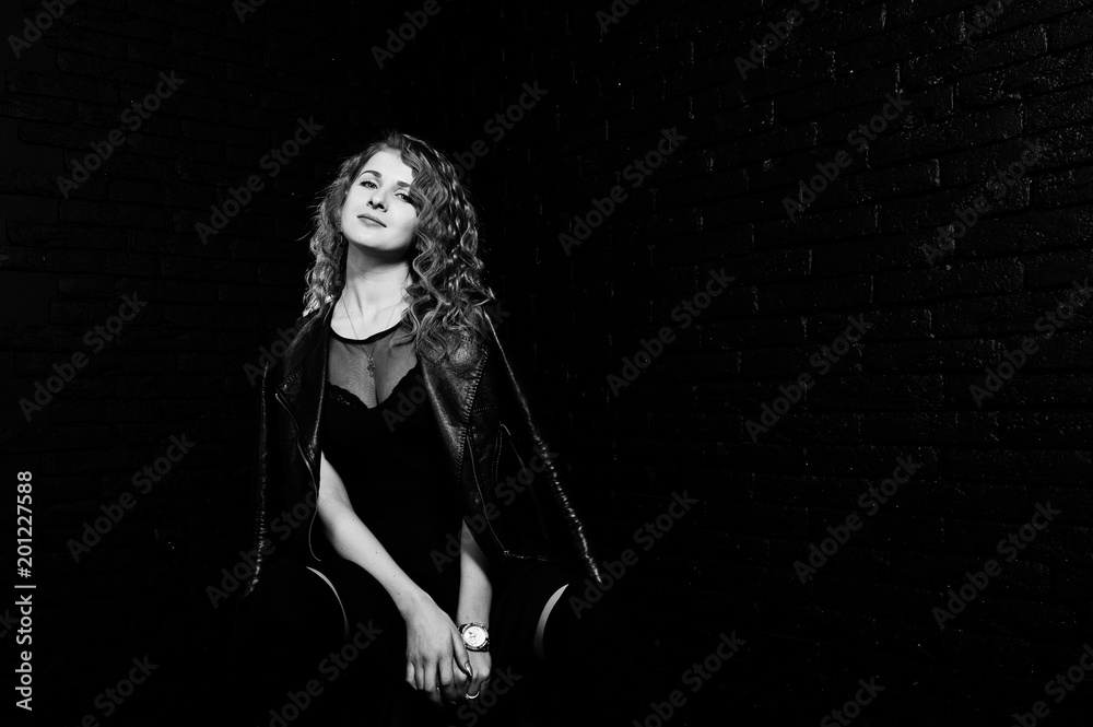 Curly hair girl at leather jacket on studio against black brick wall. Curly hair girl at leather jacket on studio against black brick wall.
