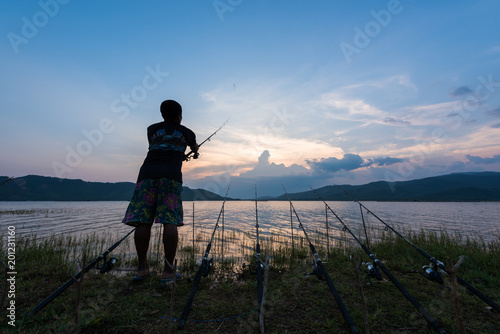 Fisherman fishing near lake on sunset