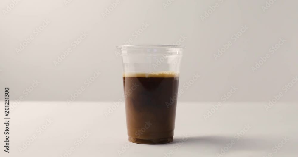 Adding milk to coffee in plastic cup on white background with reverse footage Adding milk to coffee in plastic cup on white background with reverse footage