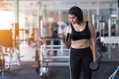 Asian woman doing workout with gym equipment and wearing sportswear to lose weight.