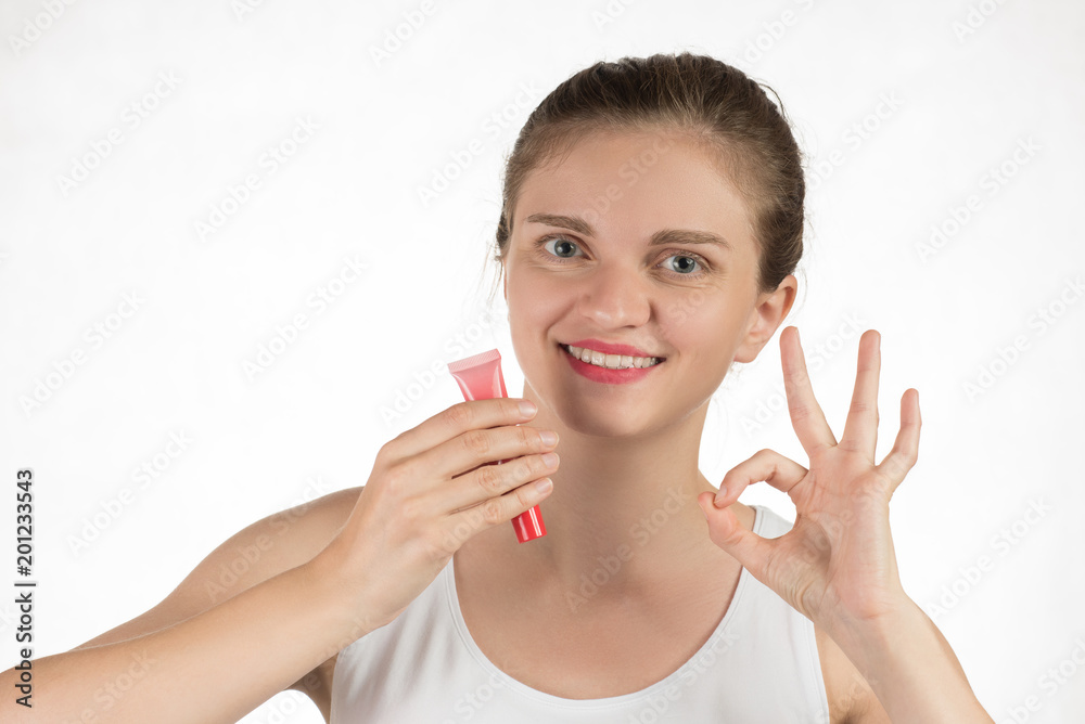 A beautiful young girl applies a persistent liquid red lipstick from a tube to her lips, and then takes it off as a film A beautiful young girl applies a persistent liquid red lipstick from a tube to her lips, and then takes it off as a film