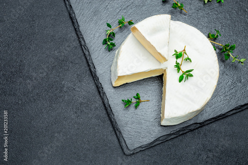 Camembert cheese and cut a slice on stone serving board