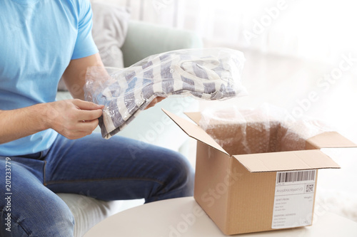 Young man unpacking parcel ...