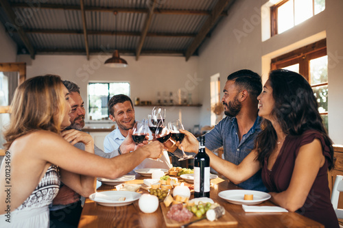 Cheerful friends toasting wine at dinner party