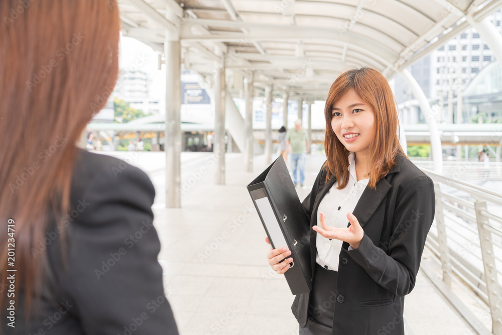 Fototapeta premium Young asian businesswoman holdind file and looking at colleague - business concept