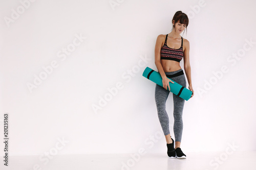 Woman standing with yoga mat in studio