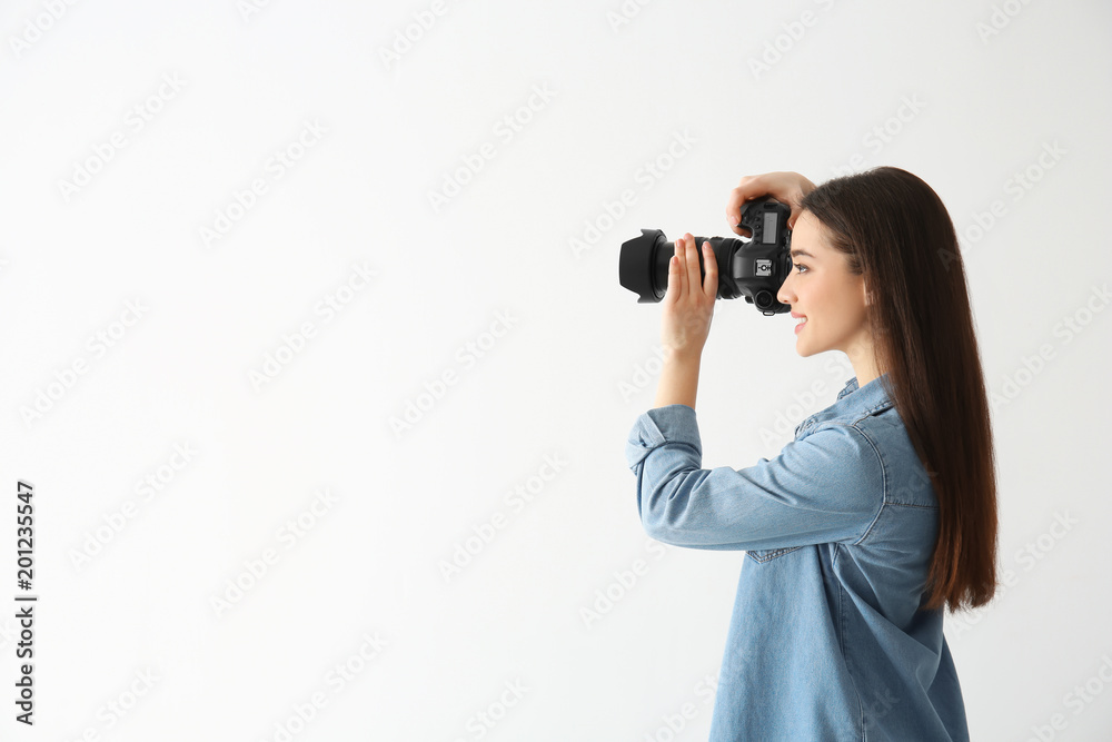 Female photographer with camera on light background Female photographer with camera on light background