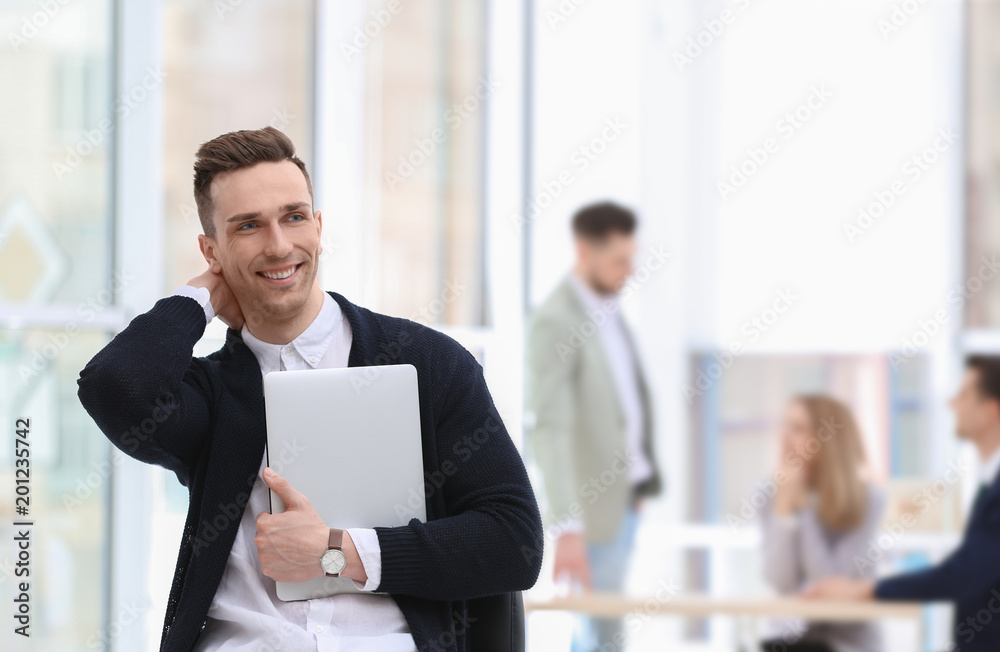 Portrait of handsome young businessman with laptop in office Portrait of handsome young businessman with laptop in office