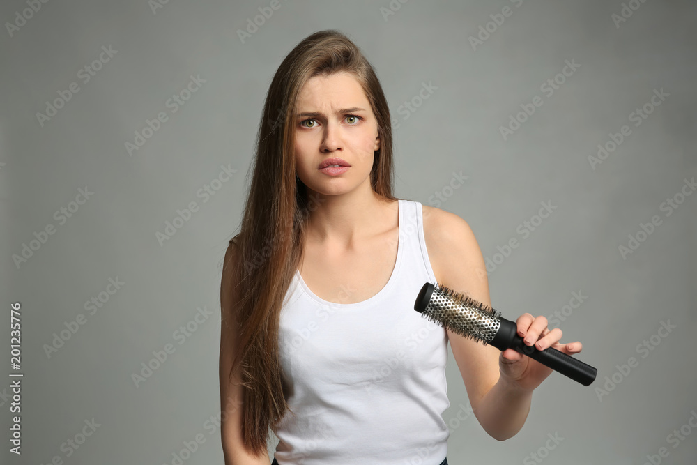 Young woman with hair loss problem on light background Young woman with hair loss problem on light background