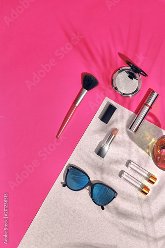 Woman's accessories lying flat on textured paper background. Pink and white colors with copy space around products.