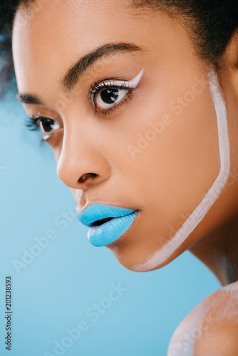 close-up portrait of young woman with creative makeup and blue lips isolated on blue