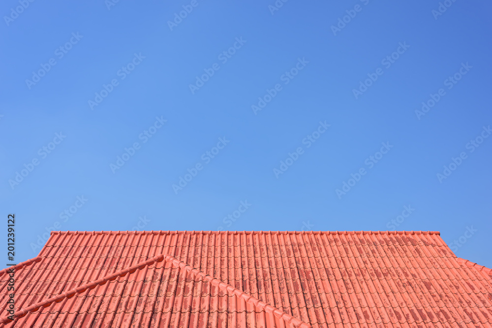 Fototapeta premium Red roof house with tiled roof on blue sky.