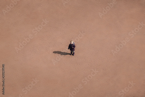 small child is standing in the middle of a sandy desert, a conceptual background.