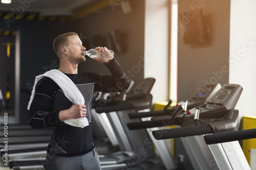 Male bodybuilder drinking water after workout