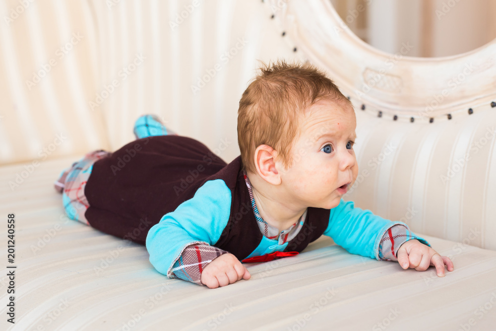 Baby boy lying on a sofa in sunny room Baby boy lying on a sofa in sunny room