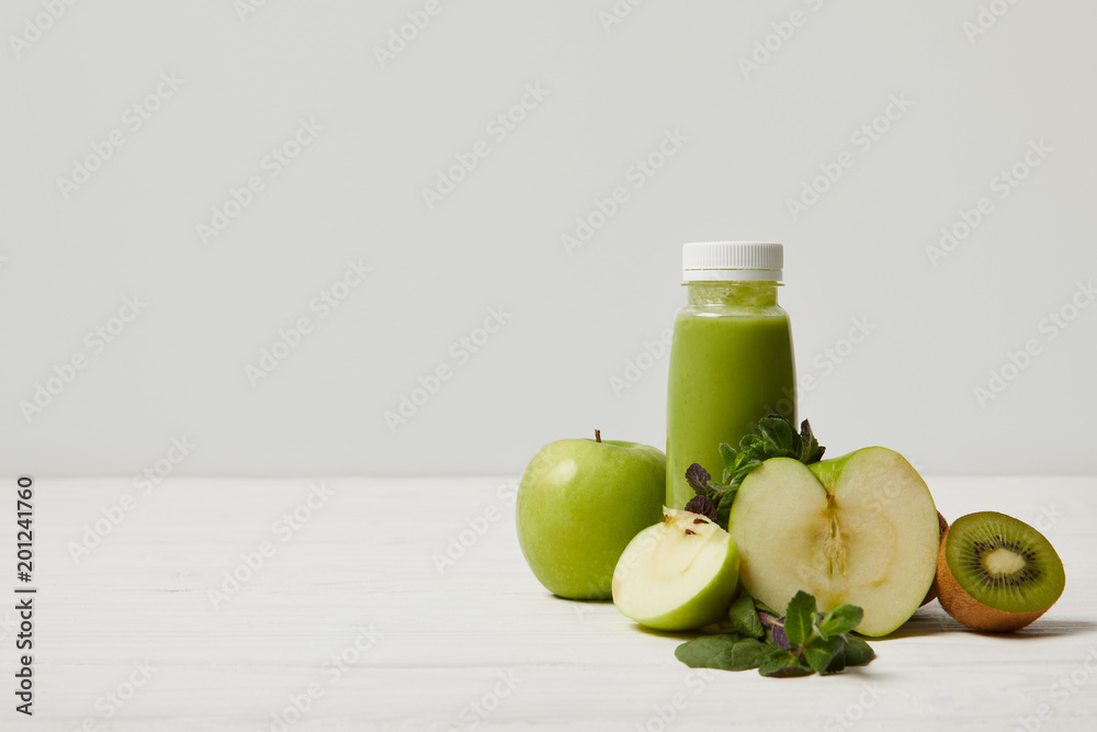 green detox smoothie with apples, kiwi and mint and on white wooden surface green detox smoothie with apples, kiwi and mint and on white wooden surface
