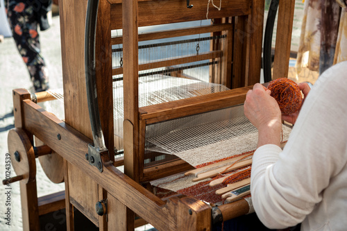 Close up hands of woman weaving color pattern on traditional hand-weaving wooden loom