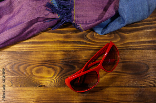 Red sunglasses and summer scarf on wooden background