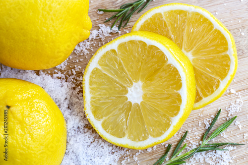 Lemon and sea salt - Beauty treatment with organic cosmetics with lemon ingredients on wood and rosemary background for body scrub and spa care.