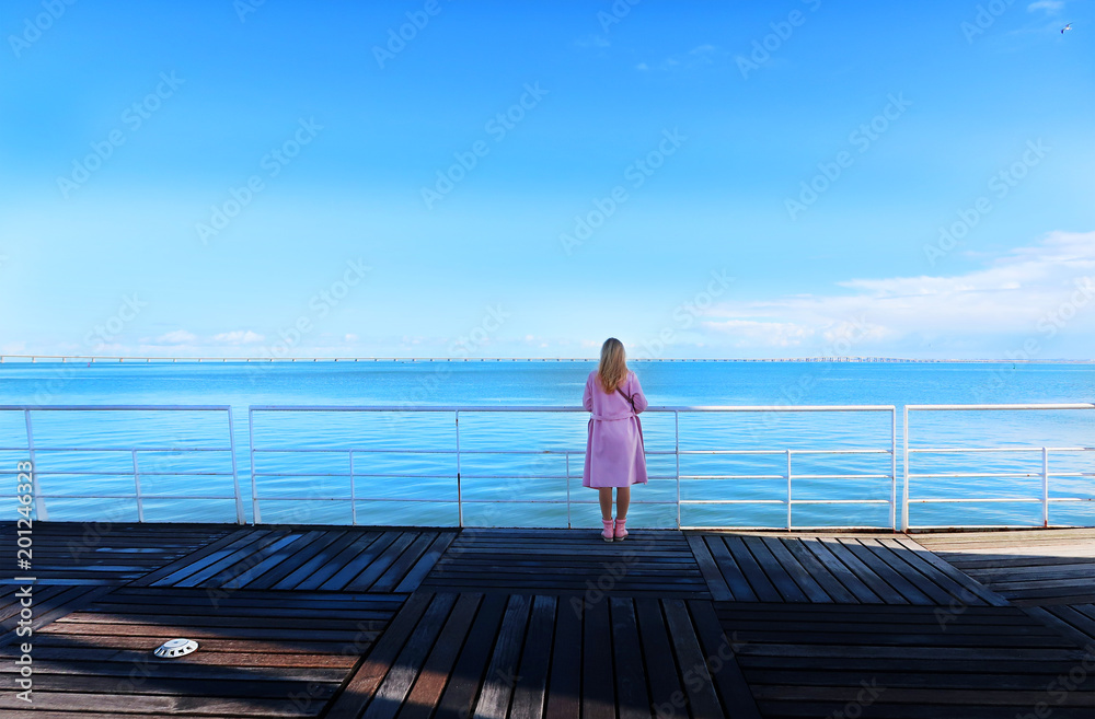 Young pretty woman standing alone on the pier near the sea Young pretty woman standing alone on the pier near the sea