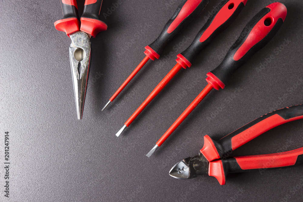 Tools electrician screwdrivers, pliers, platypuses on a black background.