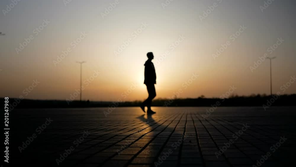 The girl is driving by on the segway against the backdrop of the sunset, and a young man is walking by her.